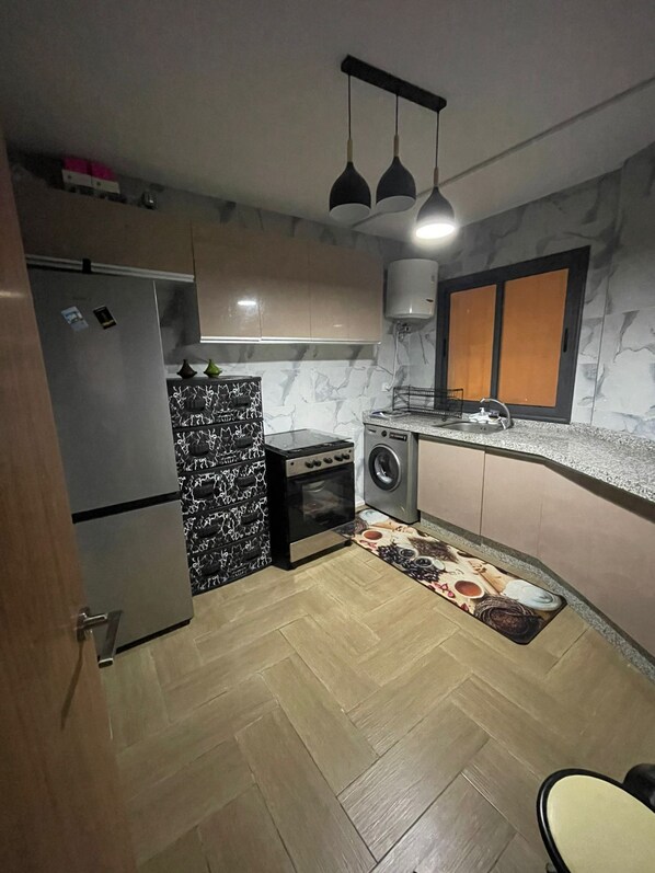 A compact kitchen with a refrigerator, stove, microwave, and sink.