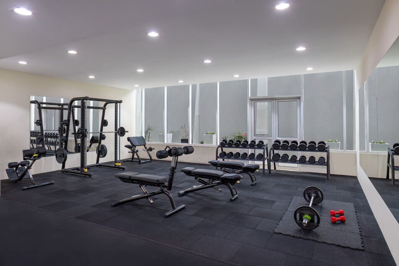 A modern gym with various weightlifting equipment, benches, and dumbbells.