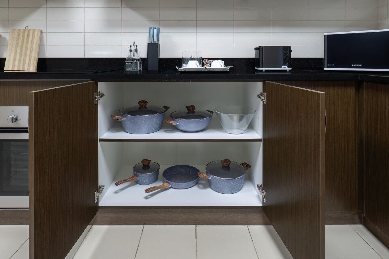 A kitchen with wooden cabinets, a black countertop, and a Samsung TV.