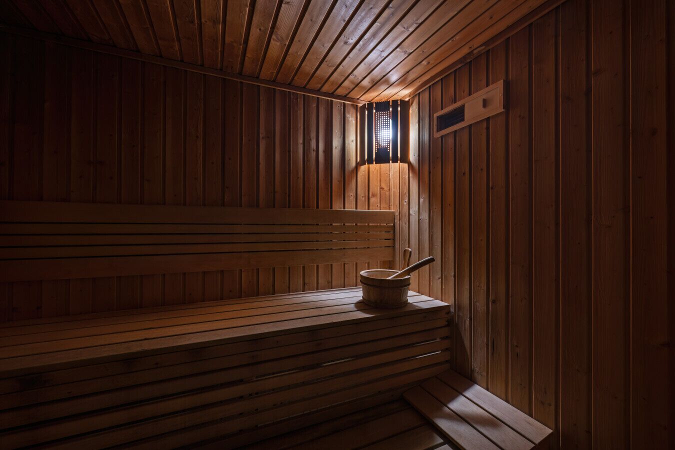 Eine Holzsauna mit Bänken und einem Holzeimer.