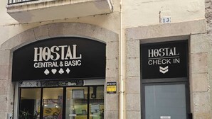 Un hostal con un cartel que dice "HOSTAL CENTRAL & BASIC" y otro cartel para "HOSTAL CHECK IN".