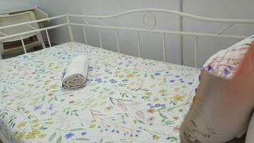 Una cama con una colcha floral, una toalla enrollada y una almohada.