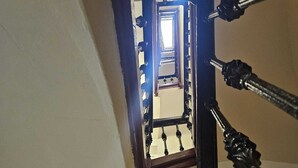 Una escalera con barandilla y balaustres de madera, que conduce a un vano abierto en la parte superior.