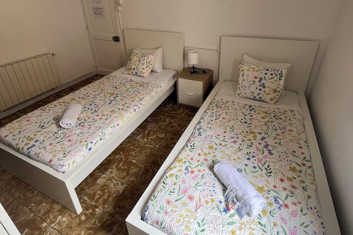 A twin room with two beds, each with floral bedding and a rolled towel.