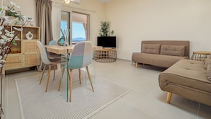 Un salon avec un canapé, une table à manger et des chaises, un téléviseur et une plante.