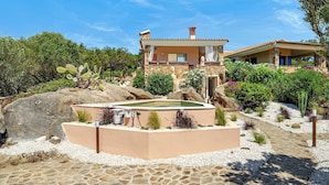 Une villa dotée d’une piscine, d’un chemin en pierre et entourée de verdure.