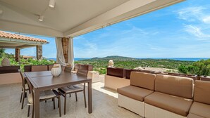 Une terrasse extérieure avec une table et des chaises pour les repas, un canapé et une vue sur le paysage.
