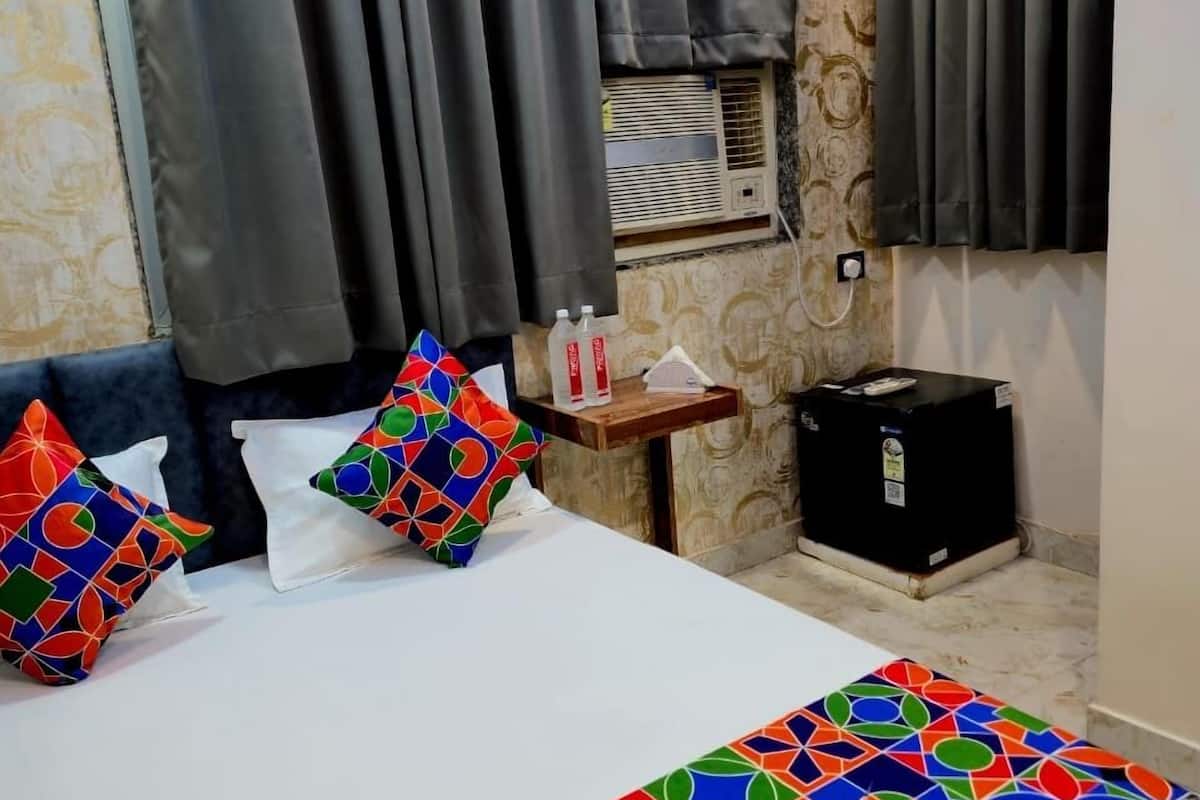 Ein Hotelzimmer mit Bett, Nachttisch, Heizung und einem Fenster mit Vorhängen.