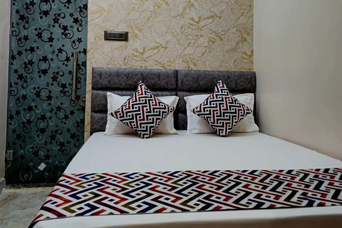 Ein Schlafzimmer mit einem Bett, zwei gemusterten Kissen, einem Deckenventilator und einer verzierten Tür.