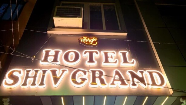 Ein Hotelschild mit der leuchtenden Aufschrift "HOTEL SHIVGRAND" in der Nacht.