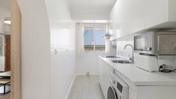 A modern kitchen with white cabinetry, a built-in oven, a microwave, and a sink.