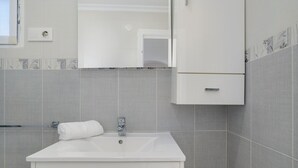Une salle de bain avec un lavabo blanc, une serviette et un miroir au-dessus.