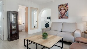 Un salon moderne avec un canapé, une table basse, un meuble et un tableau accroché au mur.