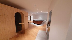 Un interior moderno con un arco de madera que conduce a una zona central con un grupo de asientos y una escalera.