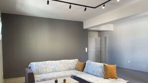 Una sala de estar moderna con un sofá seccional, una mesa de centro de madera y una pared de acento gris.
