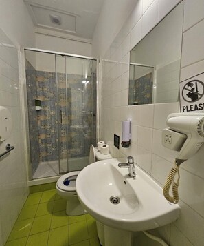 Une salle de bain équipée d’une douche, de toilettes, d’un lavabo et d’un sèche-mains.