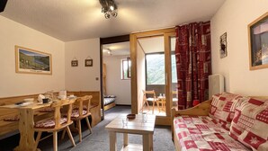 Une pièce chaleureuse avec une table à manger en bois, des chaises, un canapé et un lit.