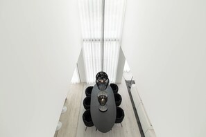 A modern dining area with a dark oval table, six black chairs, and a unique black chandelier.