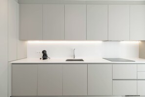 A modern kitchen with white cabinetry, a stainless steel sink, and a built-in range hood.