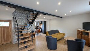 Een modern interieur met een houten trap, een bank en een televisie.