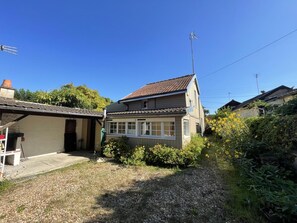 En boligejendom med et toetagers hus, skorsten og en have med grus og beplantning.