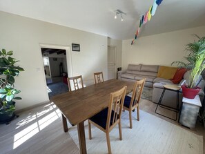 Et spiseområde med et træbord og stole, en sofa og en potteplante.