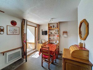A dining area with a wooden table and chairs, a bookshelf, a television, and a mirror on the wall. - Studio 4 pax, south balcony, pets allowed, parking (Les Menuires)