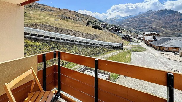 A balcony with a view of a train, a mountainous landscape, and a small village. - Studio 4 pax, south balcony, pets allowed, parking (Les Menuires)