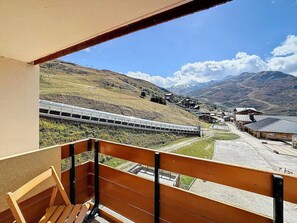 A balcony with a view of a train, a mountainous landscape, and a small village. - Studio 4 pax, south balcony, pets allowed, parking (Les Menuires)