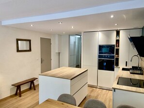 Cozinha moderna com bancada de madeira, eletrodomésticos embutidos e um banco.
