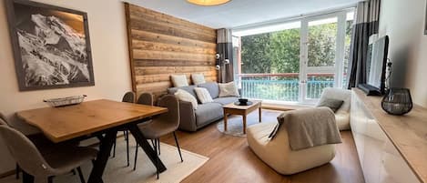 Un salon moderne avec un mur d’accent en bois, un coin repas et un ensemble de canapés.