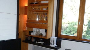 Eine kleine Küche mit Holzböden, einer Kaffeemaschine und einem Fernseher auf einem Beistelltisch.