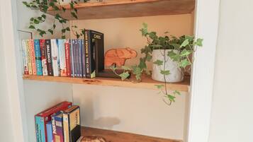Uma estante com livros, uma pequena planta e uma escultura de madeira.