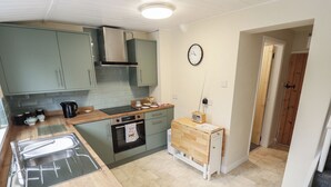 A compact kitchen with a wooden countertop, a built-in oven, and a small wooden table. - Conisholme (Grimsby)