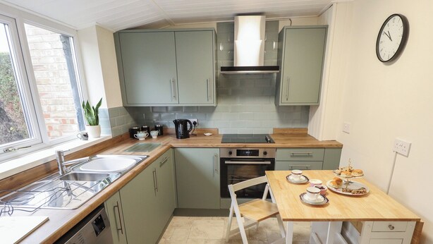 A compact kitchen with a washing machine, a sink, a stove, and a dining table with chairs. - Conisholme (Grimsby)