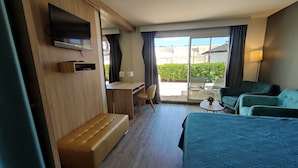 A hotel room with a bed, a desk, a chair, a sofa, and a TV.