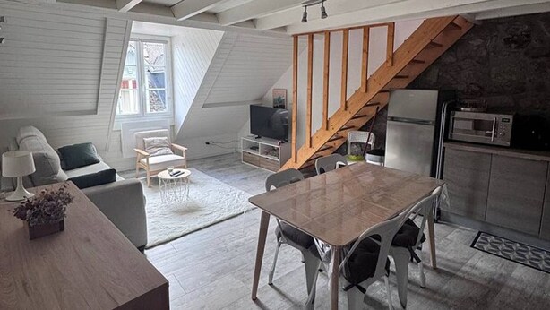 A loft-style apartment with a dining area, kitchen, and living space.
