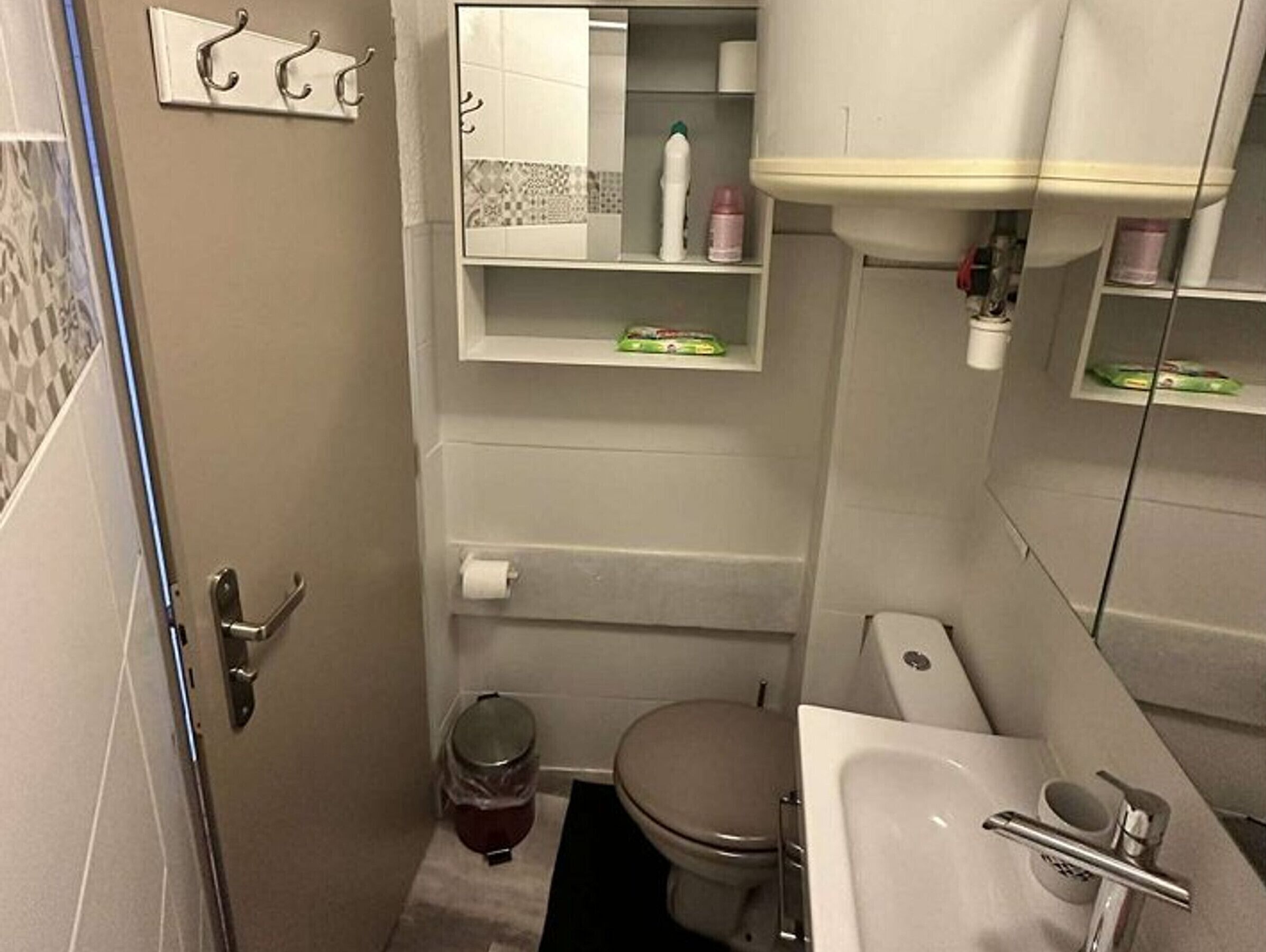 Une petite salle de bain comprenant des toilettes, un lavabo et une petite poubelle.
