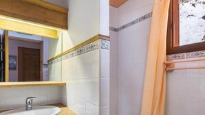 Een badkamer met een houten wastafelmeubel, een wastafel en een spiegel.