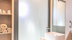 A modern bathroom with a white sink, a mirror, and a shelf with rolled towels. - Chalet for 4 near ski lifts, mountain view (Aussois)