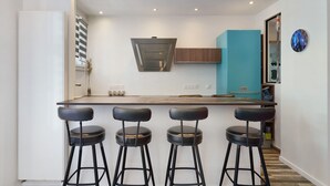 Una cucina moderna con isola centrale, sgabelli da bar e un orologio appeso al muro.