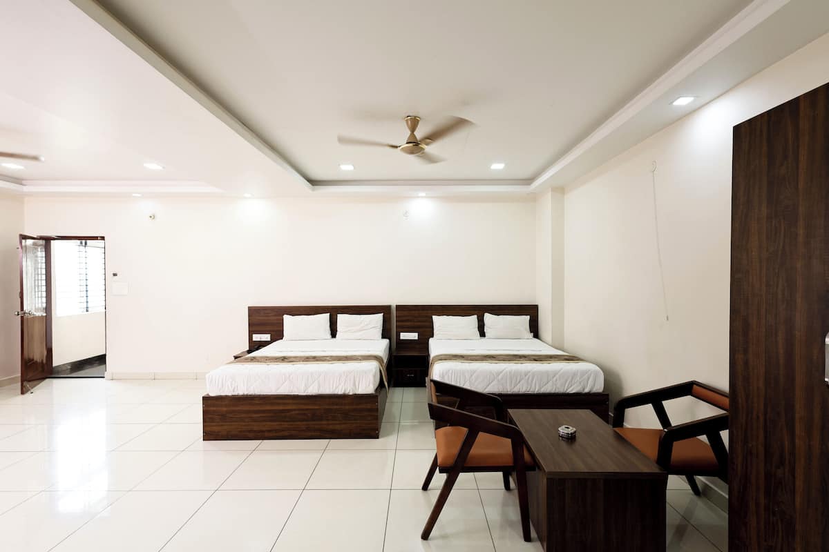 A hotel room with two beds, a desk, and a chair.
