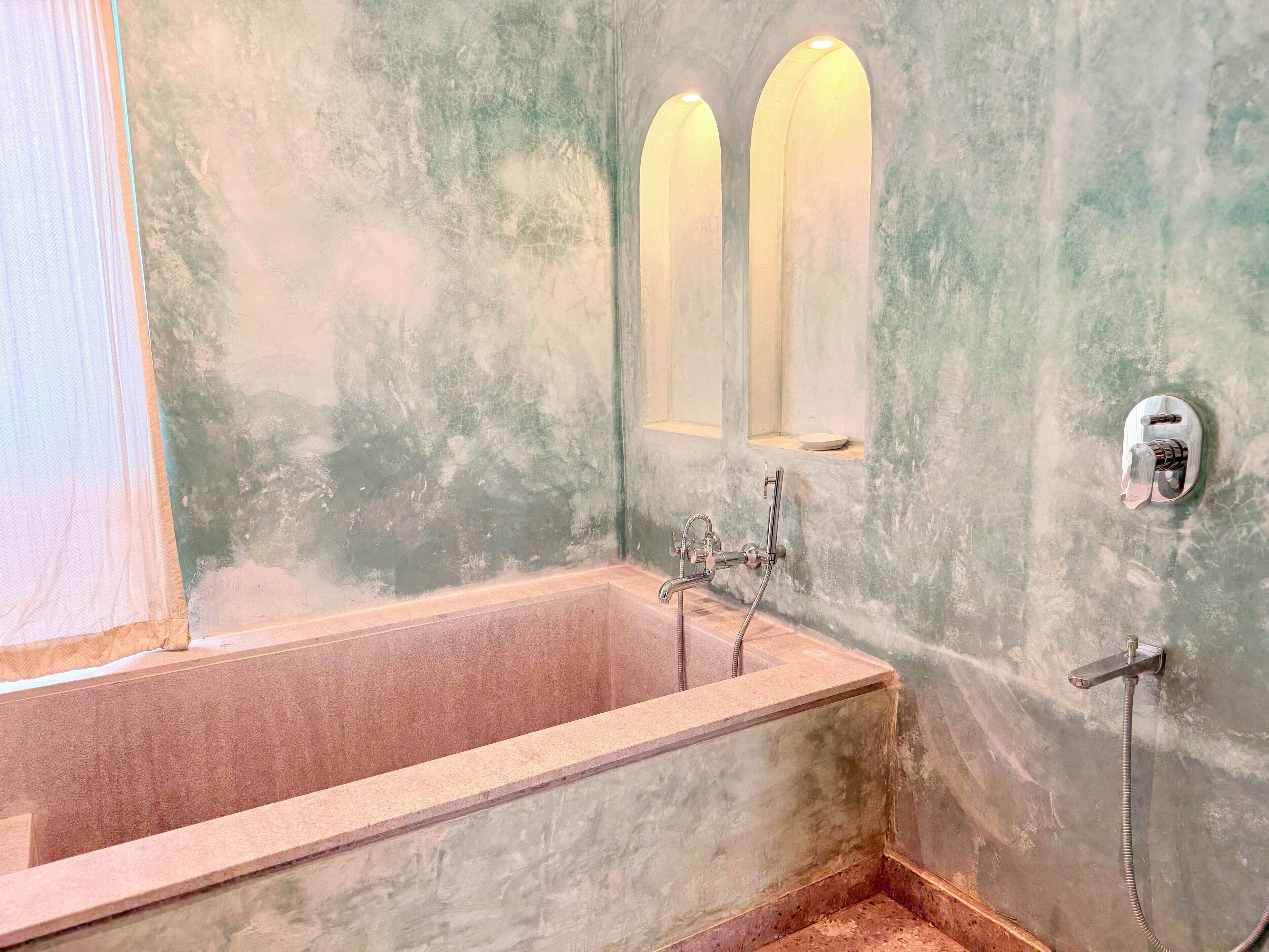 A bathroom with a bathtub, a shower, and two wall-mounted lights.