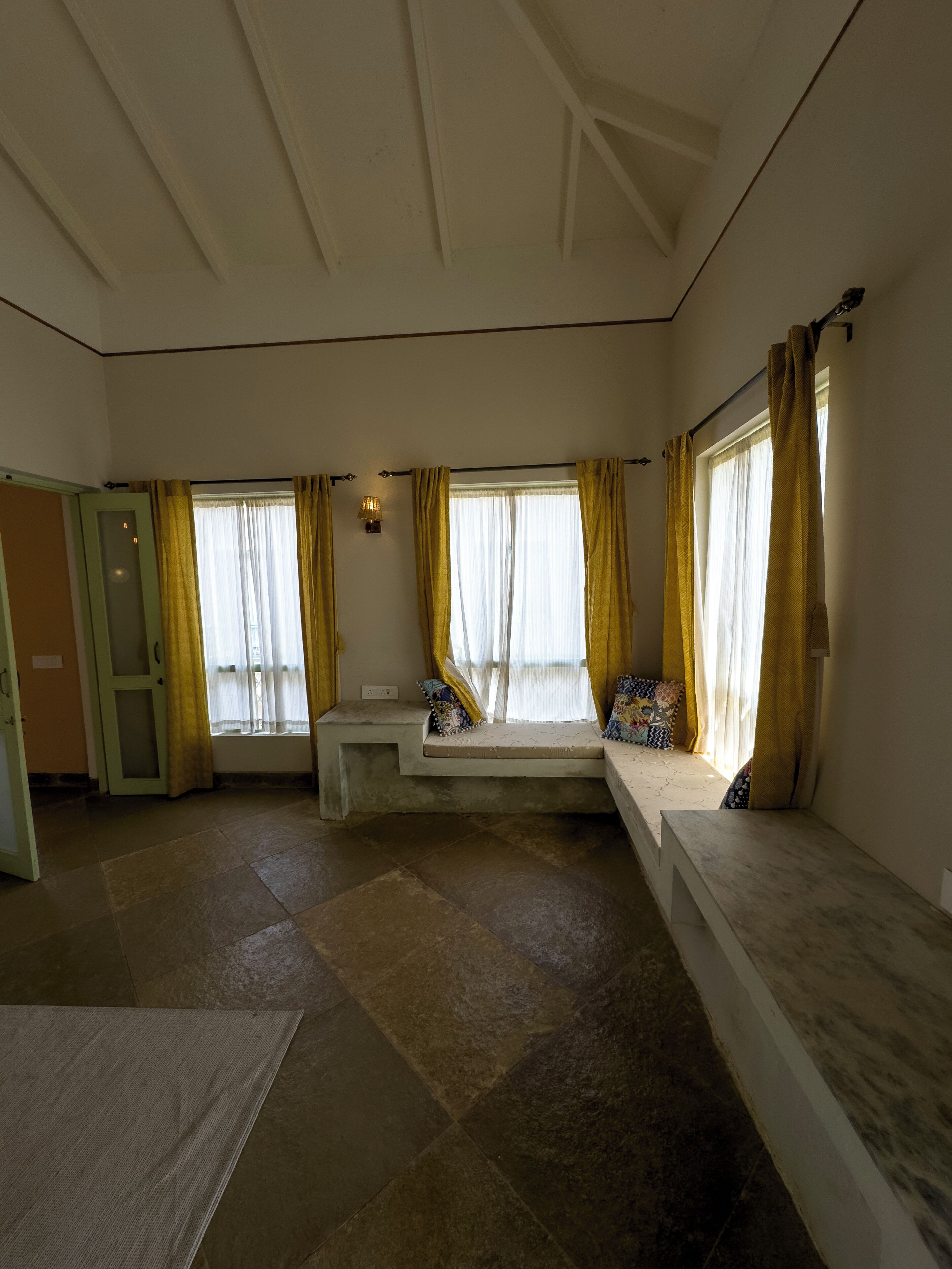 A room with a built-in bench along the windows, a small table, and a door.