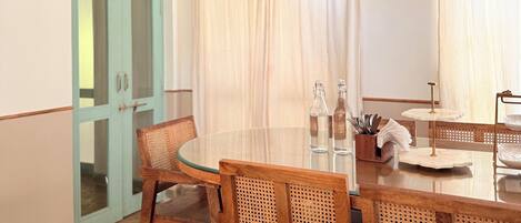 Un comedor con una mesa redonda, sillas de mimbre y un ventilador de techo.