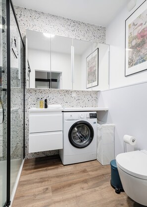 Una lavanderia piccola e funzionale con lavatrice, lavello e WC.