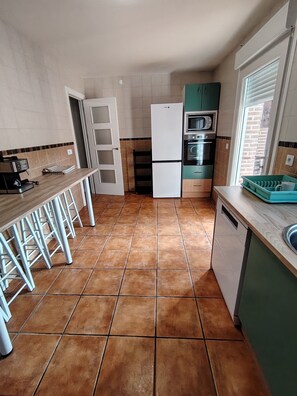 Una cocina compacta equipada con refrigerador, horno y microondas, junto a un comedor con taburetes.