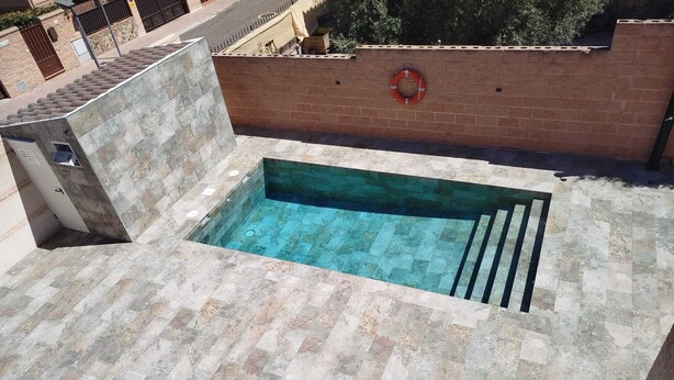 A rooftop swimming pool with a tiled deck and a brick wall. - El Balcon a Toledo 10 min from puy du fou (Cobisa)
