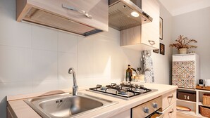 Une cuisine moderne dotée d’un évier en acier inoxydable, d’une cuisinière à gaz, de meubles en bois et d’un dosseret carrelé.