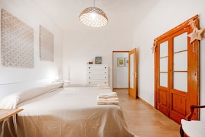 A bedroom with a bed, bedside table, dresser, and a wooden door with star decorations.